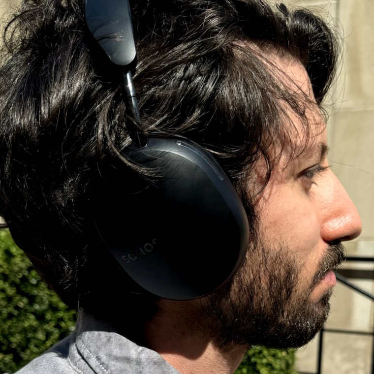 A side profile of a man wearing the Sonos Ace headphones outdoors.