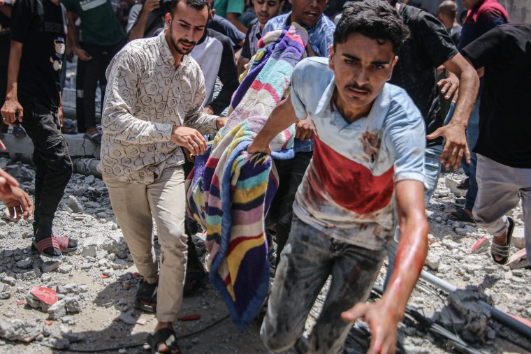 Palestinians carry a body away from the scene among rubble