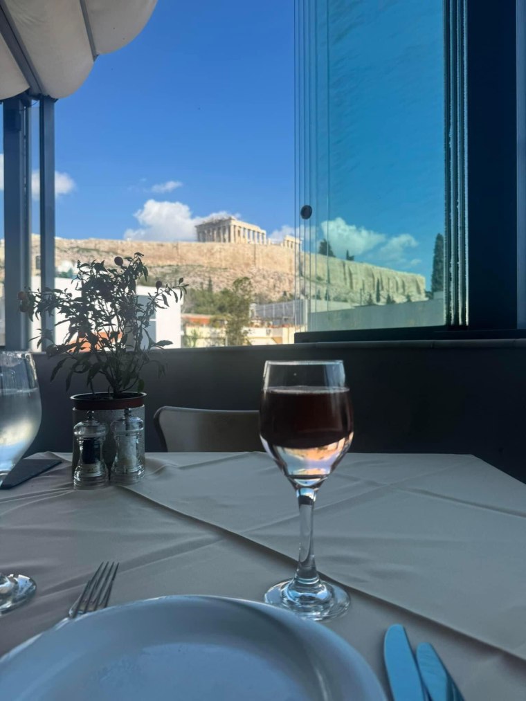 glass of wine in front of Greece ruins