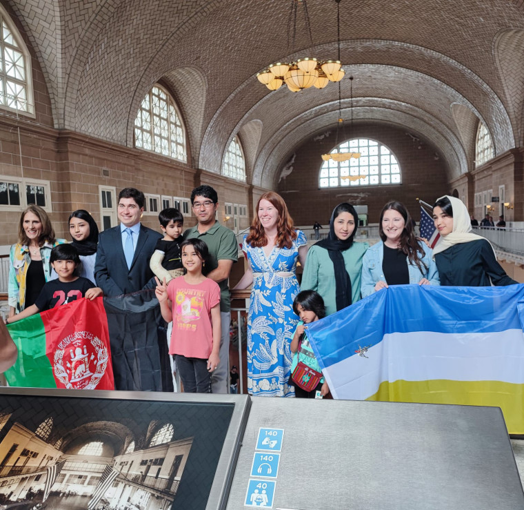 Zahra Shahnoory, second left back row, on Ellis Island along with her mentor Bethany Thorne, center wearing floral dress, and Andrew Heinrich, the family’s immigration attorney, third left. The flag on the right is the Hazara flag.