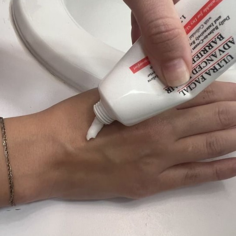 Woman squeezes the barrier cream out of its tube and onto the back of her hand.