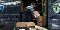 An Amazon delivery driver removes packages from a truck outside