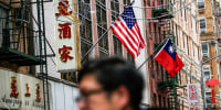 A blurred person close to the frame walks through Chinatown outside