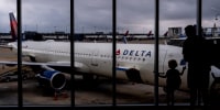 A young traveler stops to look at a Delta Airlines plane