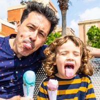 Happy father and son sitting on bench enjoying an ice cream