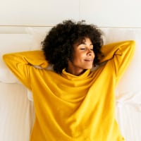 Smiling woman with closed eyes lying on bed