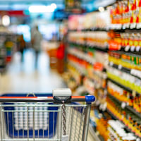 A shopping cart by a store shelf in a supermarket