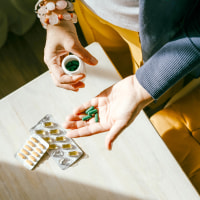 A woman standing at a table with green pills