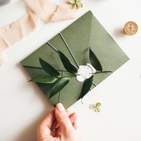 Green modern recycled paper wedding invitation on white background.