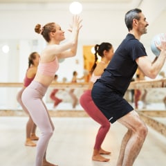 A female teacher conducts a barre fitness class.