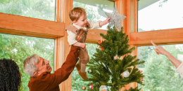 A Little boy putting up a Christmas Tree topper