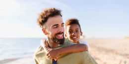 Three generation family on a beach parent piggybacking kid