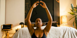 Young woman practicing breathing exercise in bedroom at home