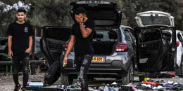 Image: A man walks between damaged cars on Oct. 12, 2023 near Kibbutz Beeri