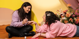 one woman painting another woman's nails