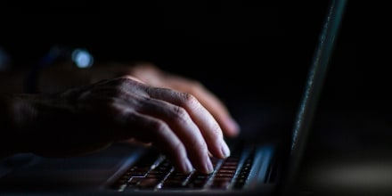 Close up of hands typing on laptop. Night work concept.