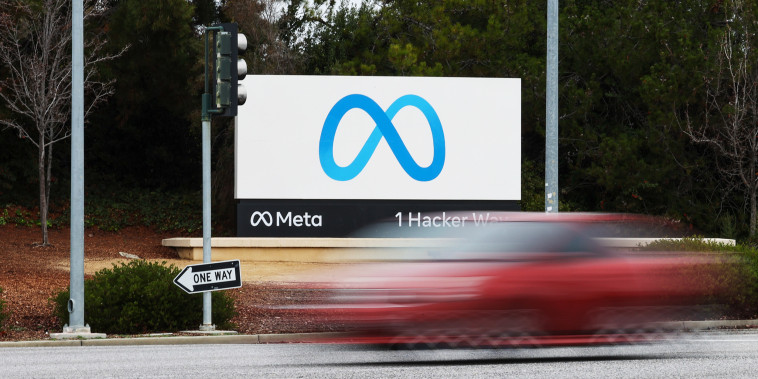 A red car drives by the Meta sign at the company's headquarters in Menlo Park