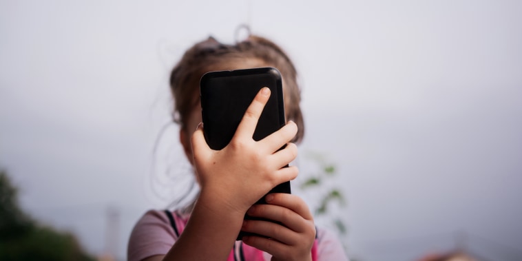 Close-up of child using mobile phone. 