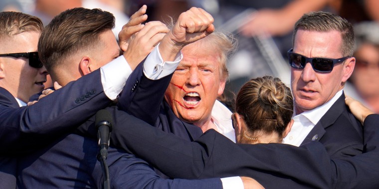 U.S. Secret Service agents hold Trump as he pumps his fist