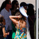 People queue under a shade.