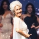 Choi Soon-hwa smiles on stage in front of other contestants, wearing a white dress