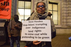 Getty Images : A demonstrator holds an anti- Adani and save Hasdeo placard during the protest. 