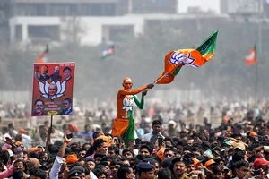 Getty Images : A Bharatiya Janata Party (BJP) supporter waves a flag among the crowd of other supporters listening to Prime Minister Narendra Modi at a rally