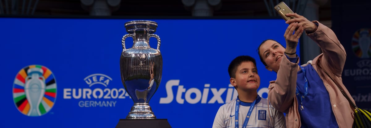 AP/Petros Giannakouris : A mother with her boy takes a selfie next to the 2024 UEFA European Championship trophy. Germany will host the Euro 2024.