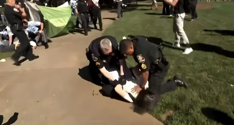 Professor Fohlin forcefully pushed to the ground by an officer.  - Screengrab