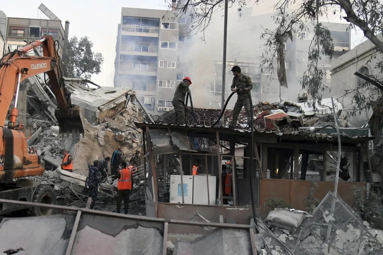 The workers clear the rubble at a destroyed building struck by Israeli jets in Damascus, Syria | - AP