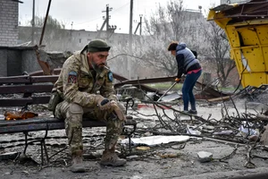 AP : A Ukrainian serviceman smokes sitting on a bench as a local resident clears debris near a building damaged in the Russian air raid in the town of Orikhiv, Zaporizhzhia region, Ukraine, Friday, Apr. 5, 2024. 