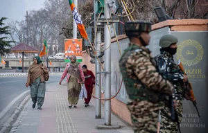  (Photo by Idrees Abbas via Getty Images) : Women walk along a street adorned with Bharatiya Janata Party (BJP) flags and boards, while Indian paramilitary troopers stand alert ahead of Prime Minister Narendra Modi's visit.