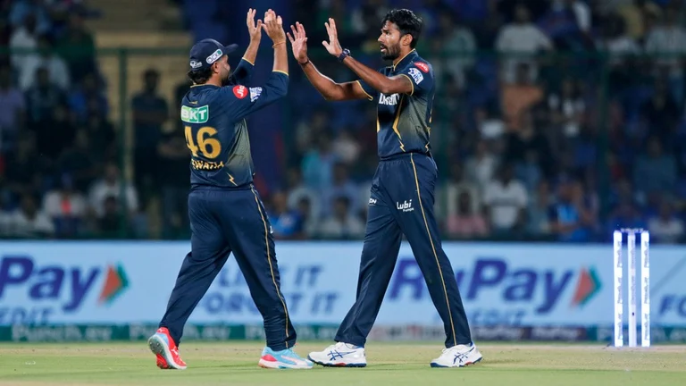 Gujarat Titans' Sandeep Warrier, right, and teammate Rahul Tewatia celebrate the wicket of Delhi Capitals' player. - AP