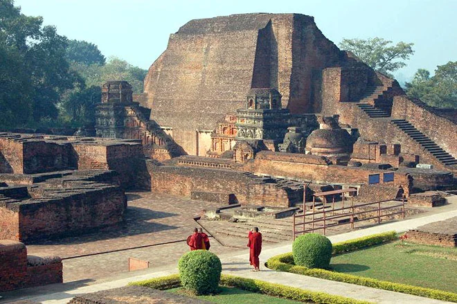 Two monks walking around Nalanda university ruins with a garden.