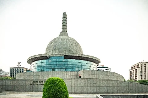 A building with a dome and a tree in front of it at Lord Buddha Smriti Park.