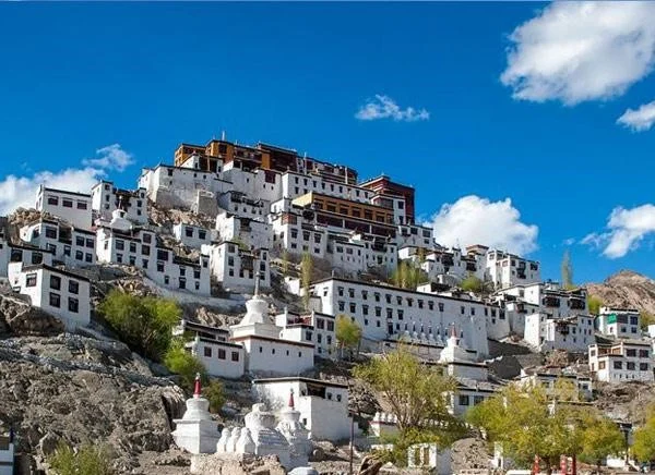 Thikse Monastery, a serene white structure nestled on a picturesque hillside.