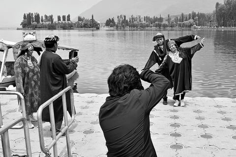 Tourists wearing traditional Kashmiri dresses pose for pictures at the Dal Lake