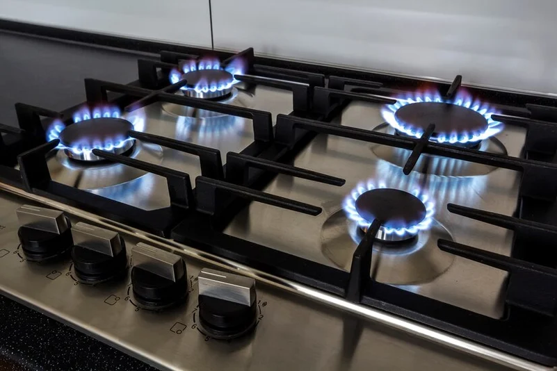 A sleek black 4 gas stove burring 