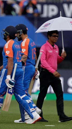 AP Photo : India's captain Rohit Sharma, left, and Virat Kohli walk off the field after rain stopped play during the ICC Men's T20 World Cup cricket match between India and Pakistan at the Nassau County International Cricket Stadium in Westbury, New York, Sunday, June 9, 2024. 

