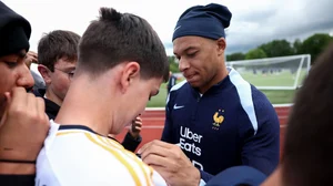 Kylian Mbappe signs a fan's Real Madrid shirt at a France training session.