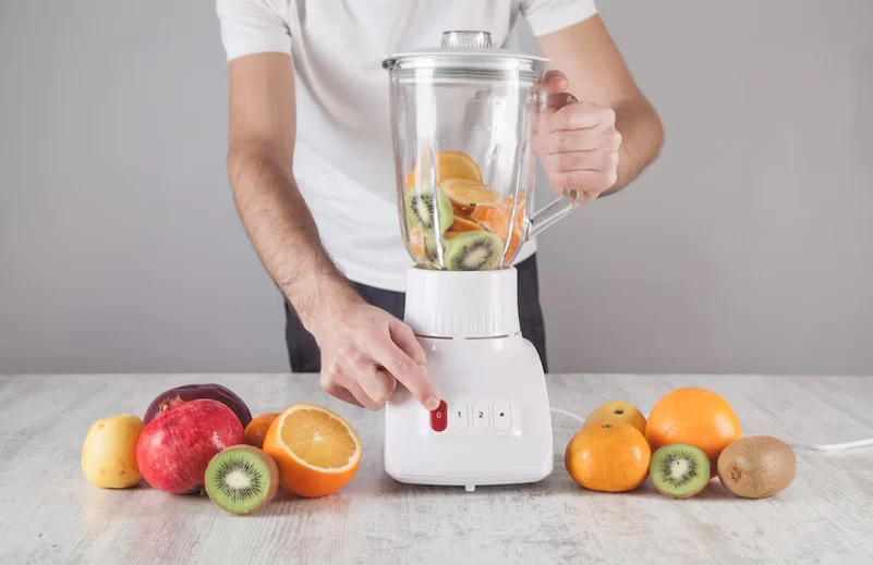 A juicer mixer grinder with fruits on the side