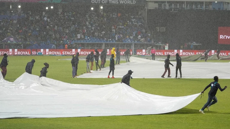 Ground staff run onto the field with covers as rain stops play during the ICC Men's T20 World Cup cricket match. - AP