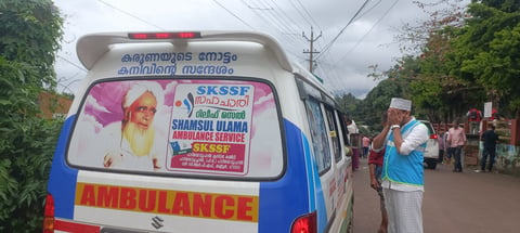 A volunteer standing in front of an ambulance amid relief operations in Wayanad, Kerala.