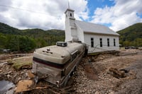 | Photo: AP/Mike Stewart : Hurricane Helene: A bus pushed by flood waters rests against Laurel Branch Baptist church