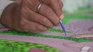 A craftsperson working on a Madhubani painting