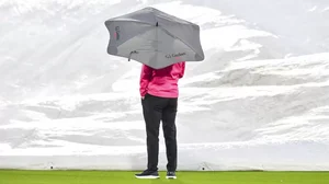 Umpire Wayne Knights watches the covers being brought on after rain stops play.