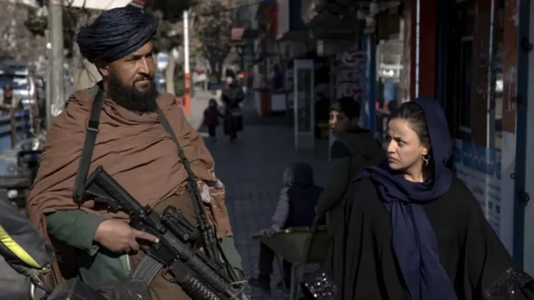 A Taliban fighter stands guard as a woman walks past in Kabul, Afghanistan, on December 26, 2022.  - null
