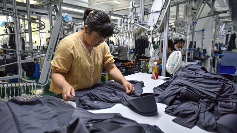 This photo taken on June 27, 2024 shows employees working on sun protection clothing at a factory in Fuyang, in eastern China's Anhui province. (Photo by AFP) / China OUT