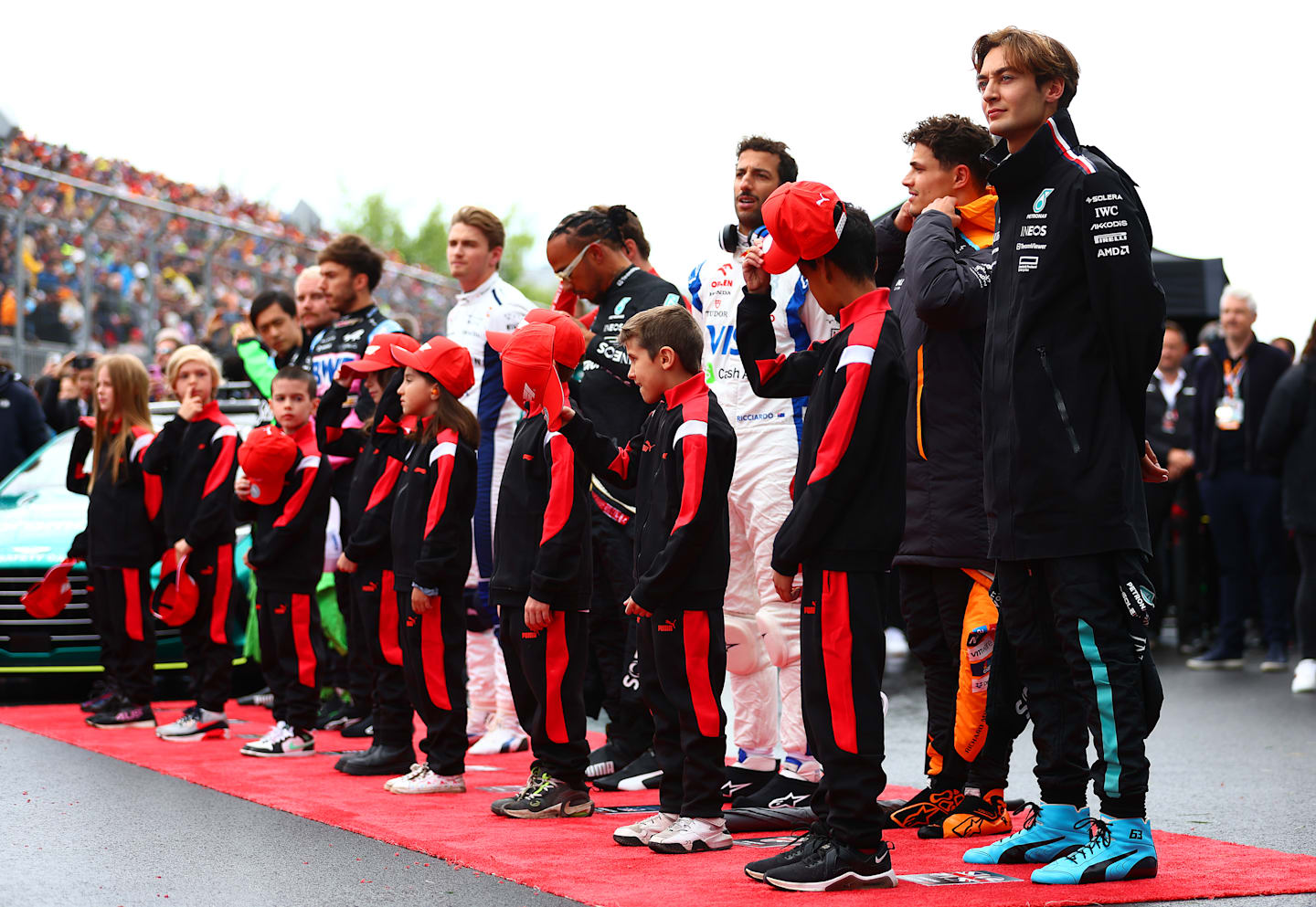 MONTREAL, QUEBEC - JUNE 09: Drivers stand with grid kids for the national anthem on the grid prior