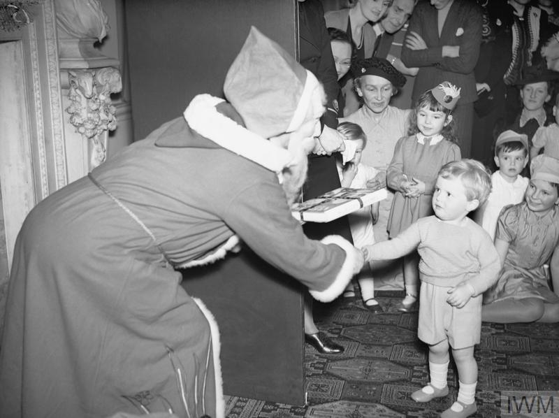 'Father Christmas' presenting Winston Churchill’s grandson with a gift at a Christmas party for Allied naval officers' children.